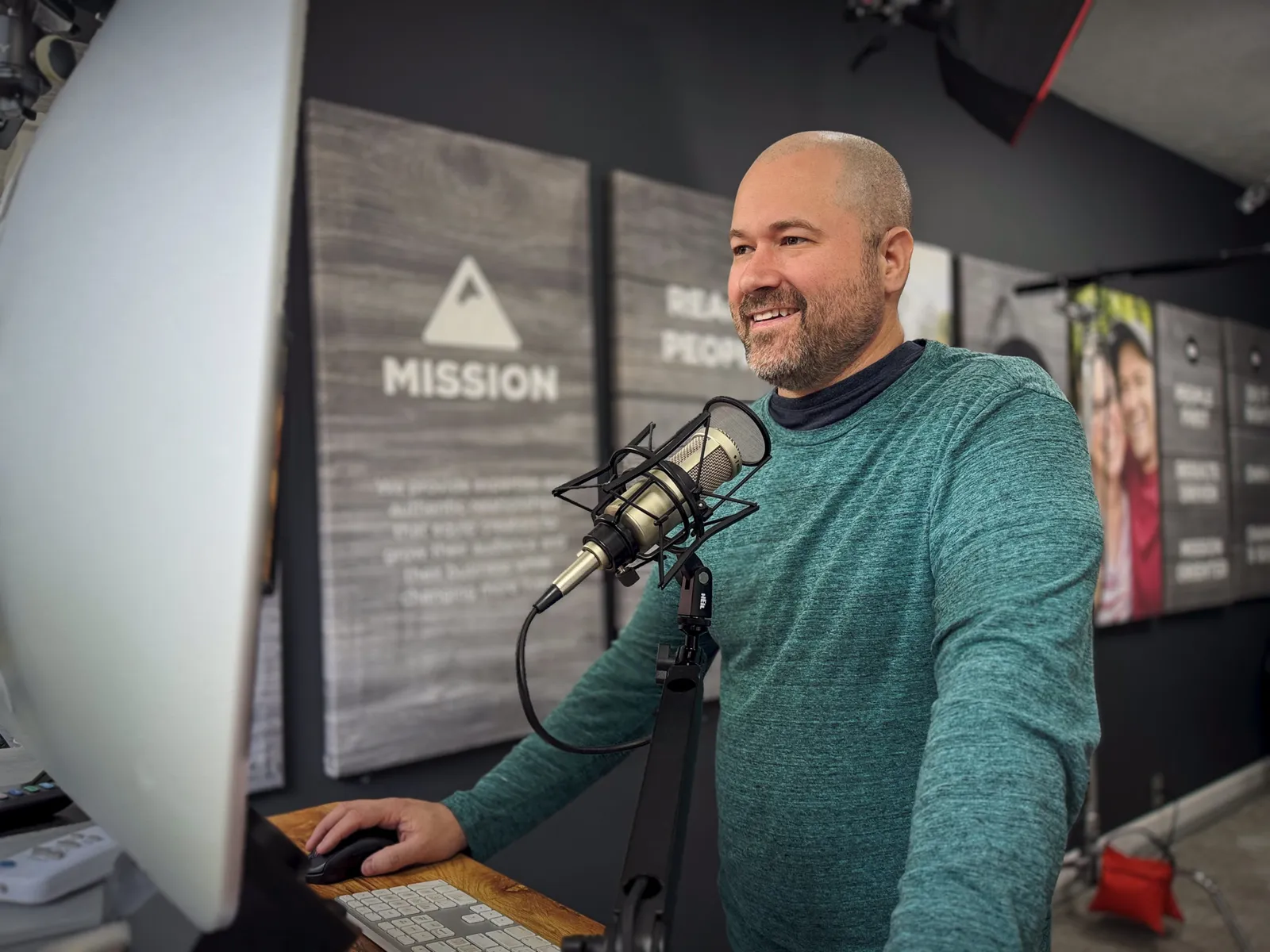 Tim Schmoyer smiling while working at a microphone in his studio